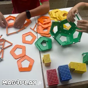 Enfant concentré construisant des formes géométriques 2D et 3D avec des barrettes magnétiques et des sphères Geomag lors d’un atelier Mag4play à Lyon, dans le Rhône, en Rhône-Alpes et en Suisse romande