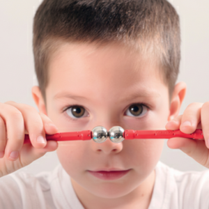 Gros plan sur le visage d'un enfant de 4 ans aux yeux écarquillés, exprimant un pur émerveillement alors qu'il observe deux aimants Geomag s'attirer ou se repousser. Cette scène de "magie scientifique" se déroule lors d'un atelier anniversaire Mag4play à Lyon, illustrant la découverte du magnétisme dans le Rhône, en Rhône-Alpes et en Suisse romande