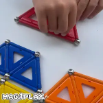 Main d’enfant qui positionne une barrette magnétique Geomag sur une structure avec sphères et panels colorés lors d’un atelier Mag4play à Lyon, dans le Rhône, en Rhône-Alpes et en Suisse romande.