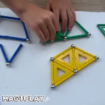 Main d’enfant qui assemble une structure Geomag avec des barrettes magnétiques, des sphères métalliques et des panels colorés lors d’un atelier Mag4play à Lyon, dans le Rhône, en Rhône-Alpes et en Suisse romande.